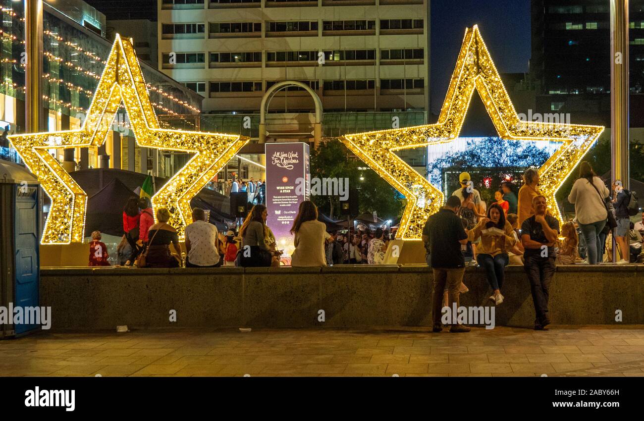 People eating in Forrest Place under 2 giant Christmas lights stars