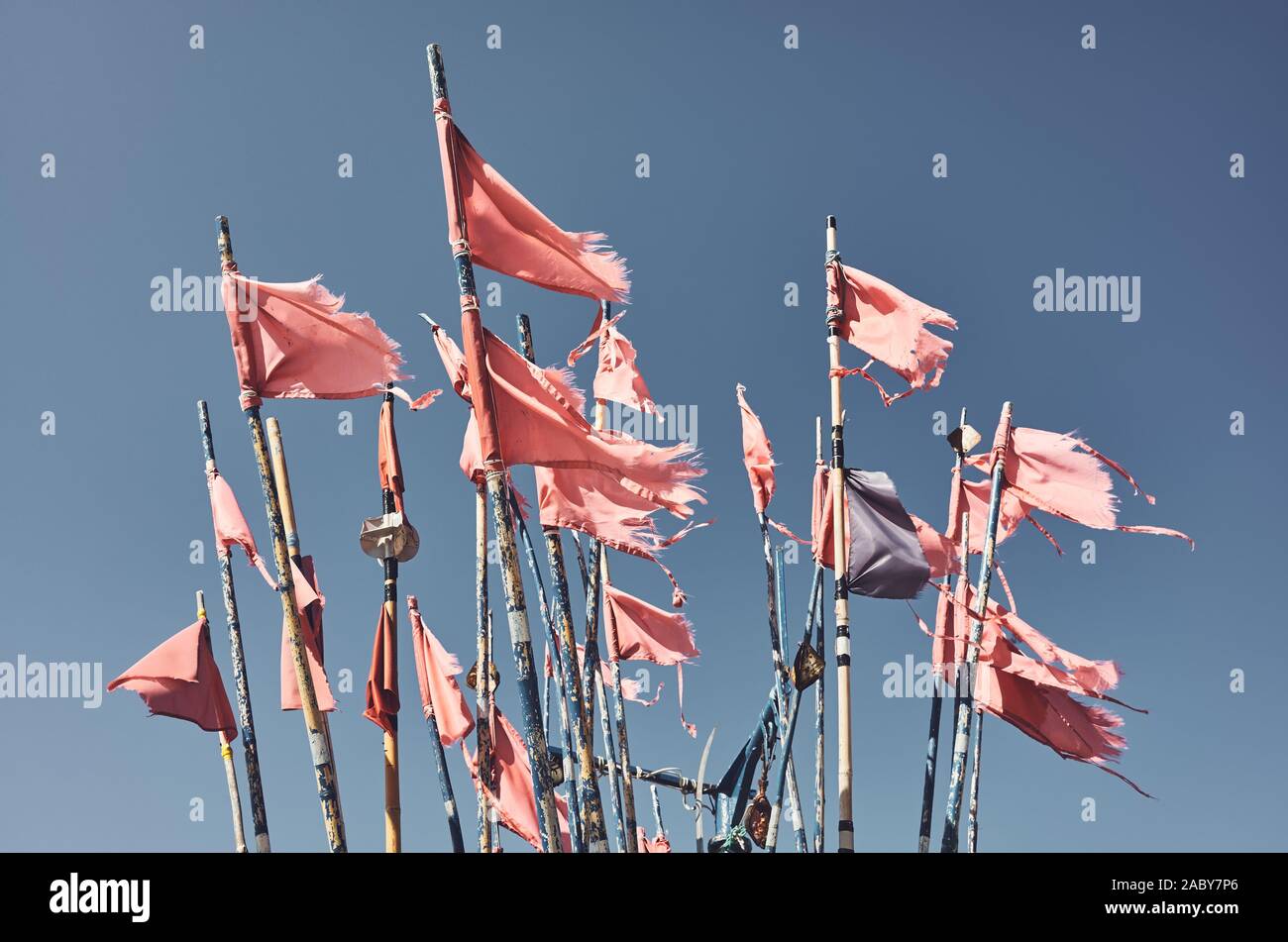 Ragged fishing marker flags against the blue sky, color toning applied. Stock Photo