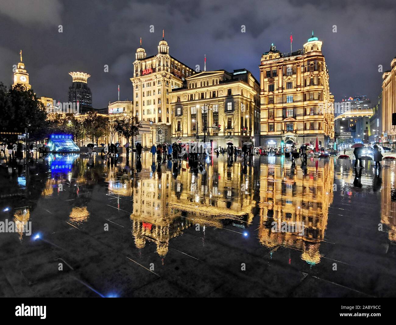 Night view of a reflection of the illuminated century-old western-style buildings on the wet ground in the rain at the promenade along the Bund in Sha Stock Photo