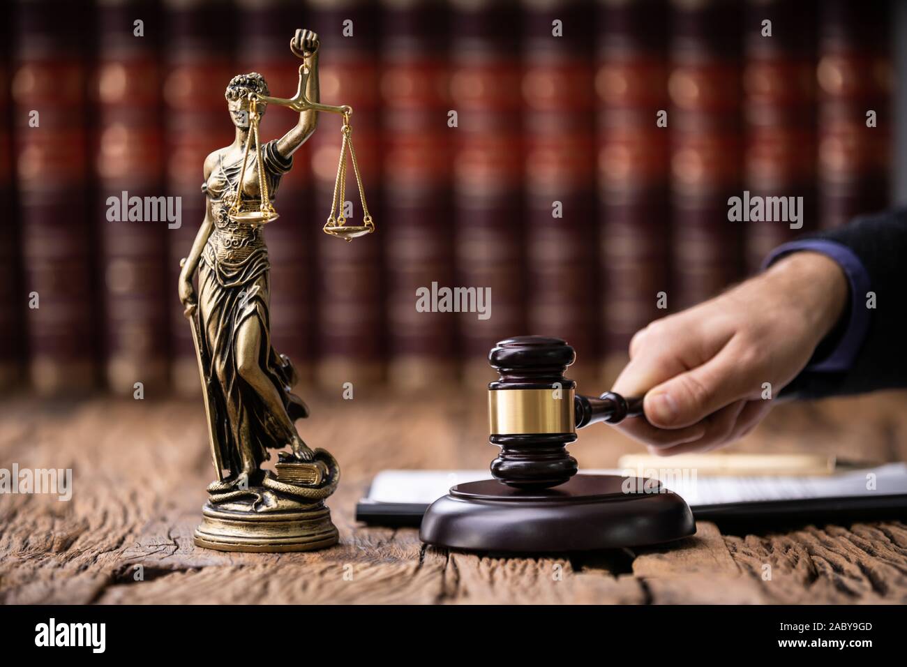 Mallet And Sounding Block With Statue Of Justice And Judge At Court Stock Photo