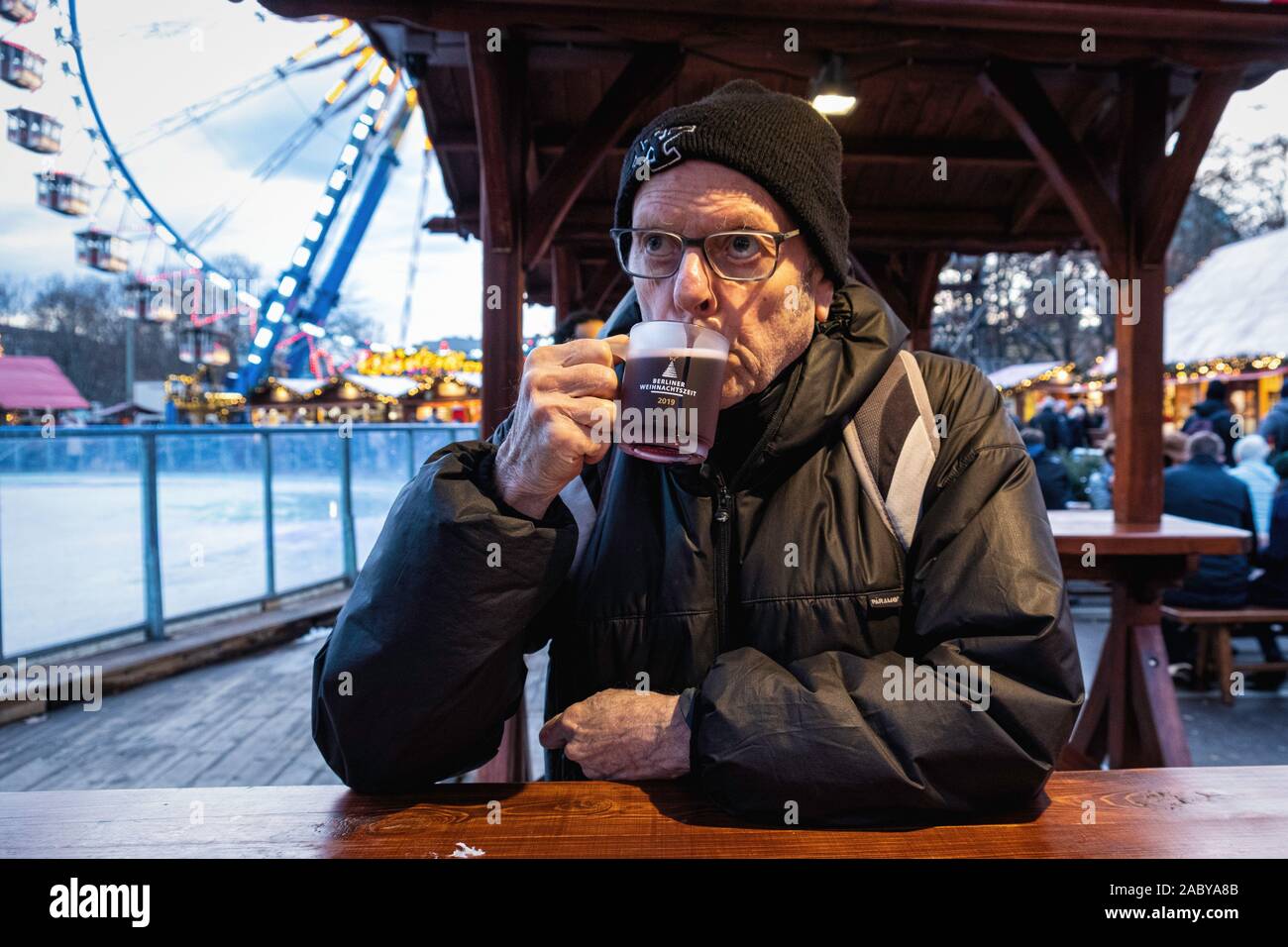 Elderly senior man drinking gluhwein at the Berliner Weihnachtzeit Christmas market, Alexanderplatz, Mitte, Berlin The Berliner Weihnachtzeit Stock Photo