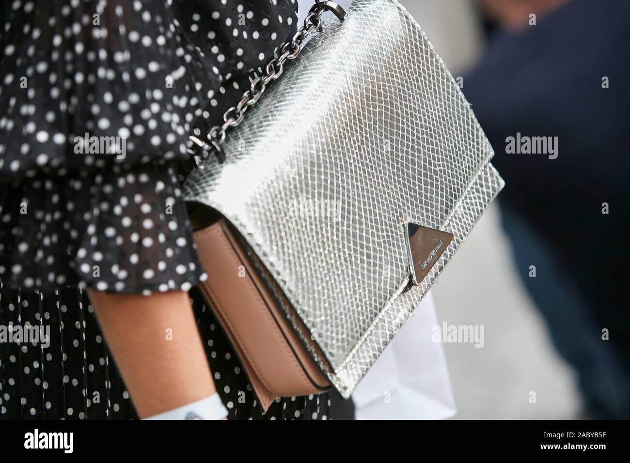 MILAN, ITALY - SEPTEMBER 19, 2019: Woman with Emporio Armani silver reptile leather bag and black and white polka dot dress before Emporio Armani fash Stock Photo