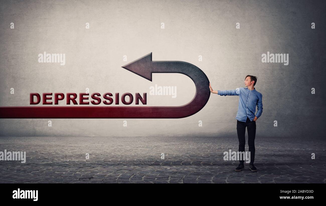 Stressless guy standing brave in front of depression, showing stop gesture, benting the arrow to reverse direction. Confident man facing problems, sta Stock Photo