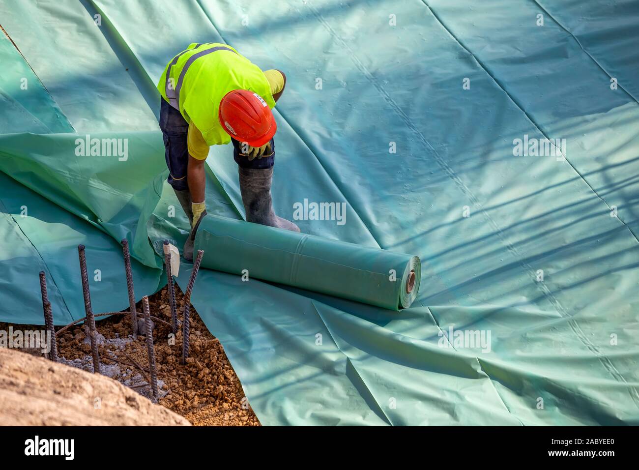 Installing plastic vapor barrier before pouring concrete slab, helping to prevent moisture from