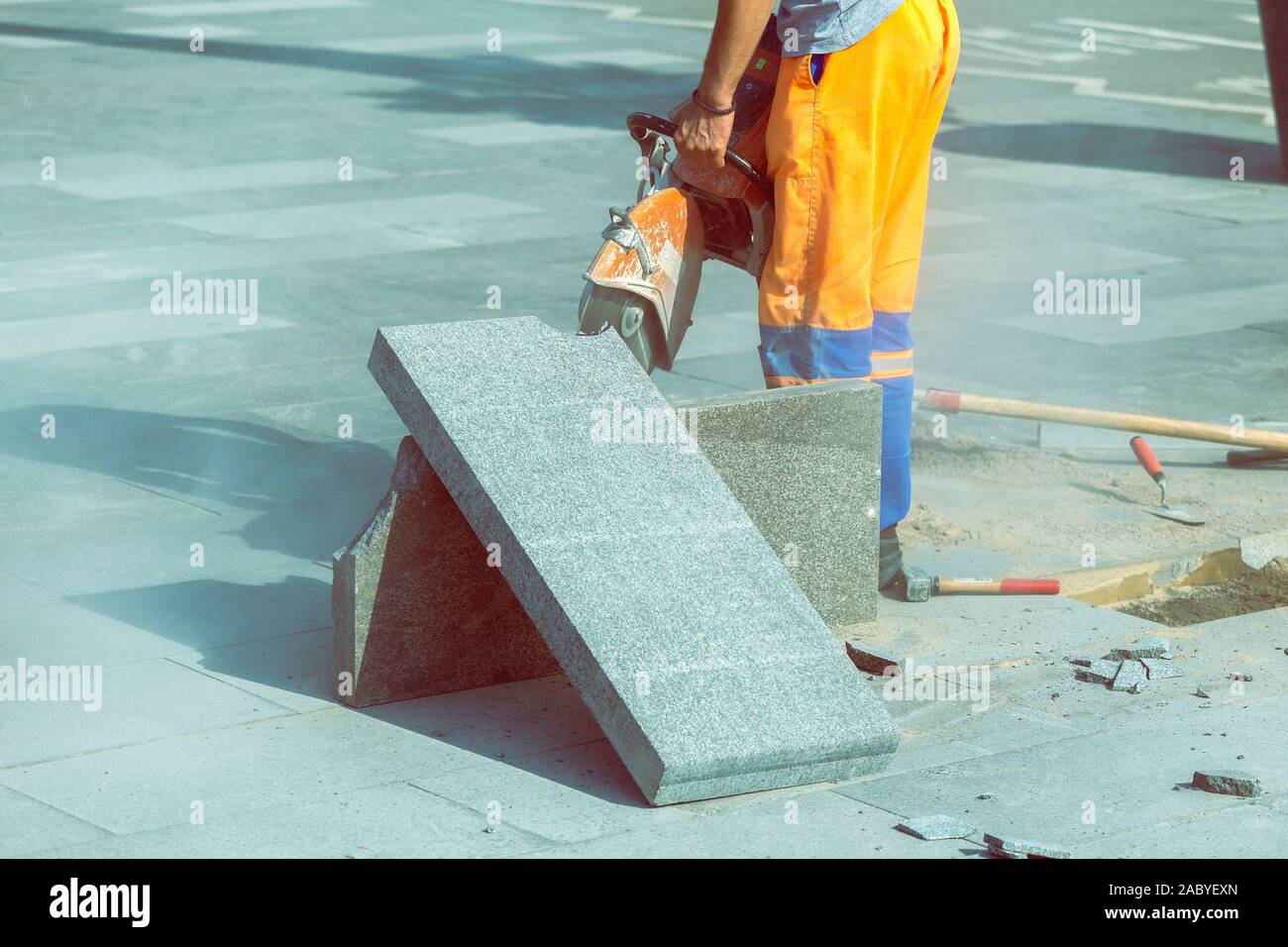 Man cutting paving slab with circular saw for repairing the walkway. Stock Photo