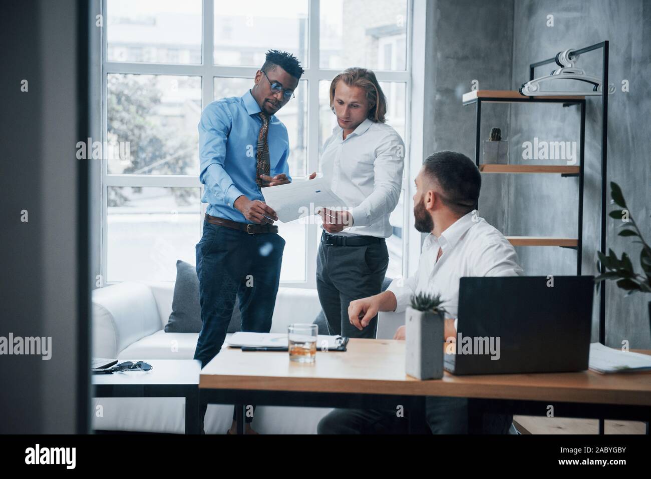 Reading a document. Three suit weared workers spending time making reports Stock Photo