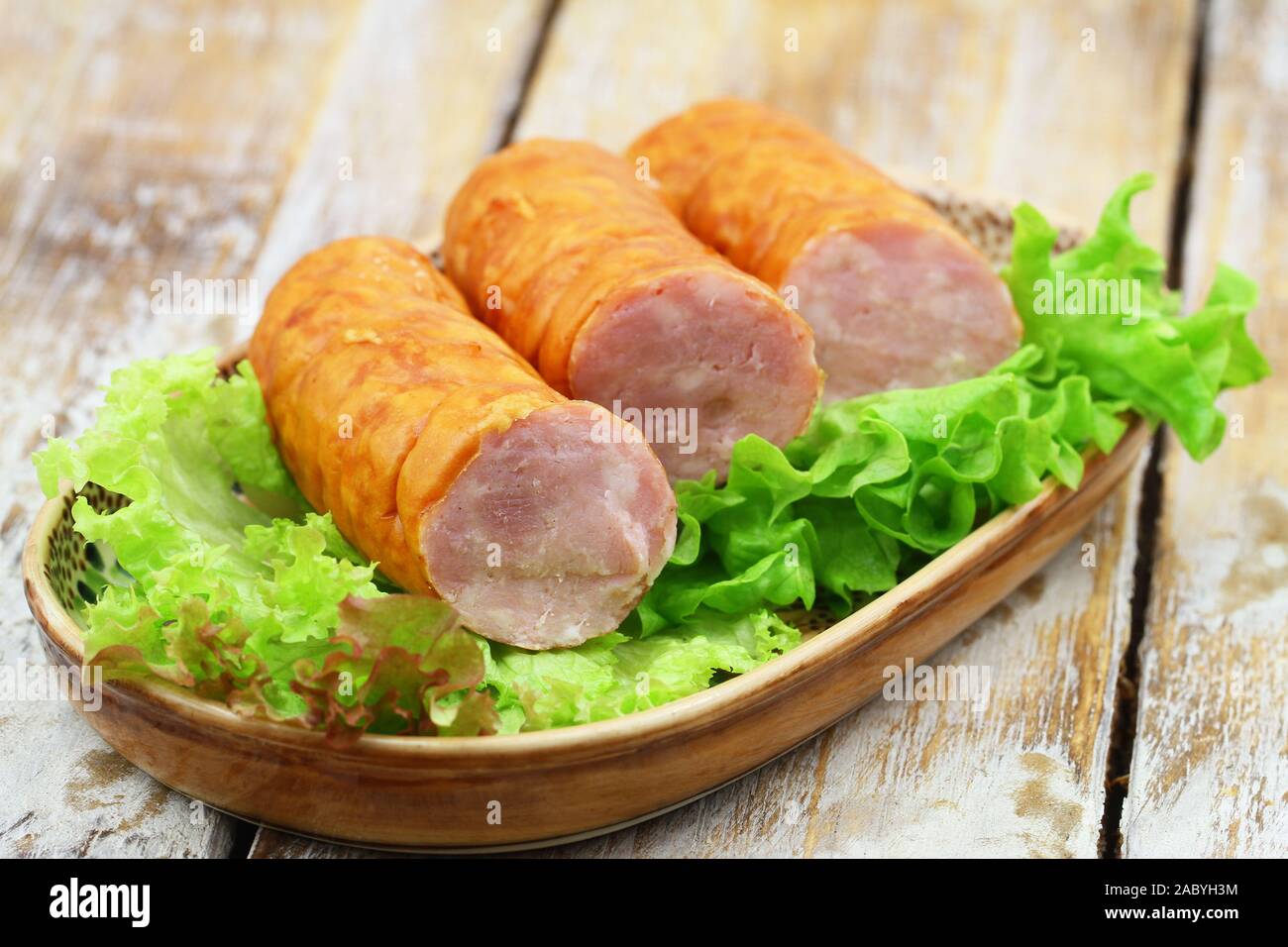 Plate of traditional Polish pork sausage on lettuce on plate on wooden surface Stock Photo