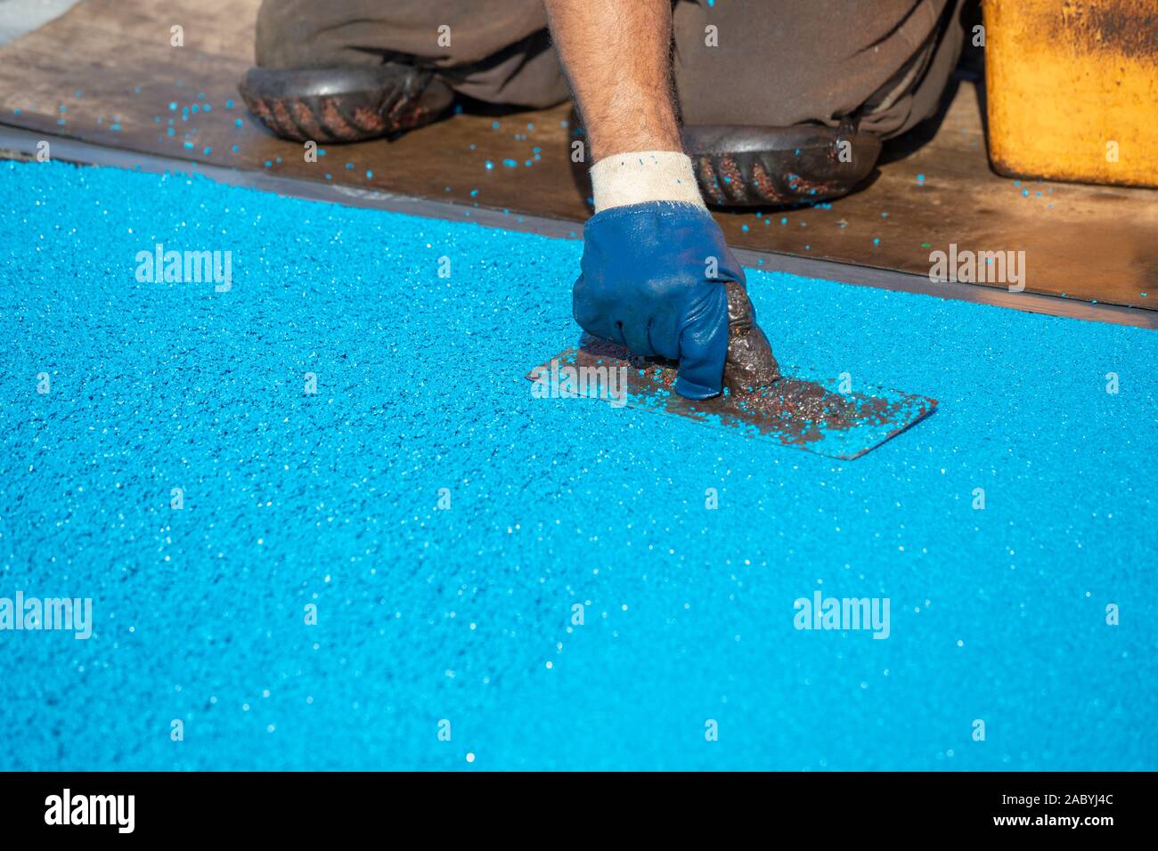 Working In Knee Pads Mason Hand Spreading Soft Rubber Crumbs