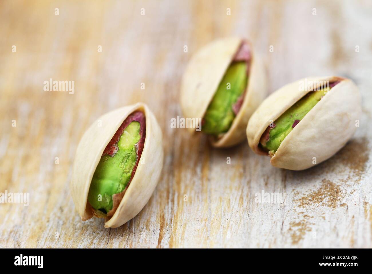 Pistachio nuts on rustic wooden surface, closeup Stock Photo