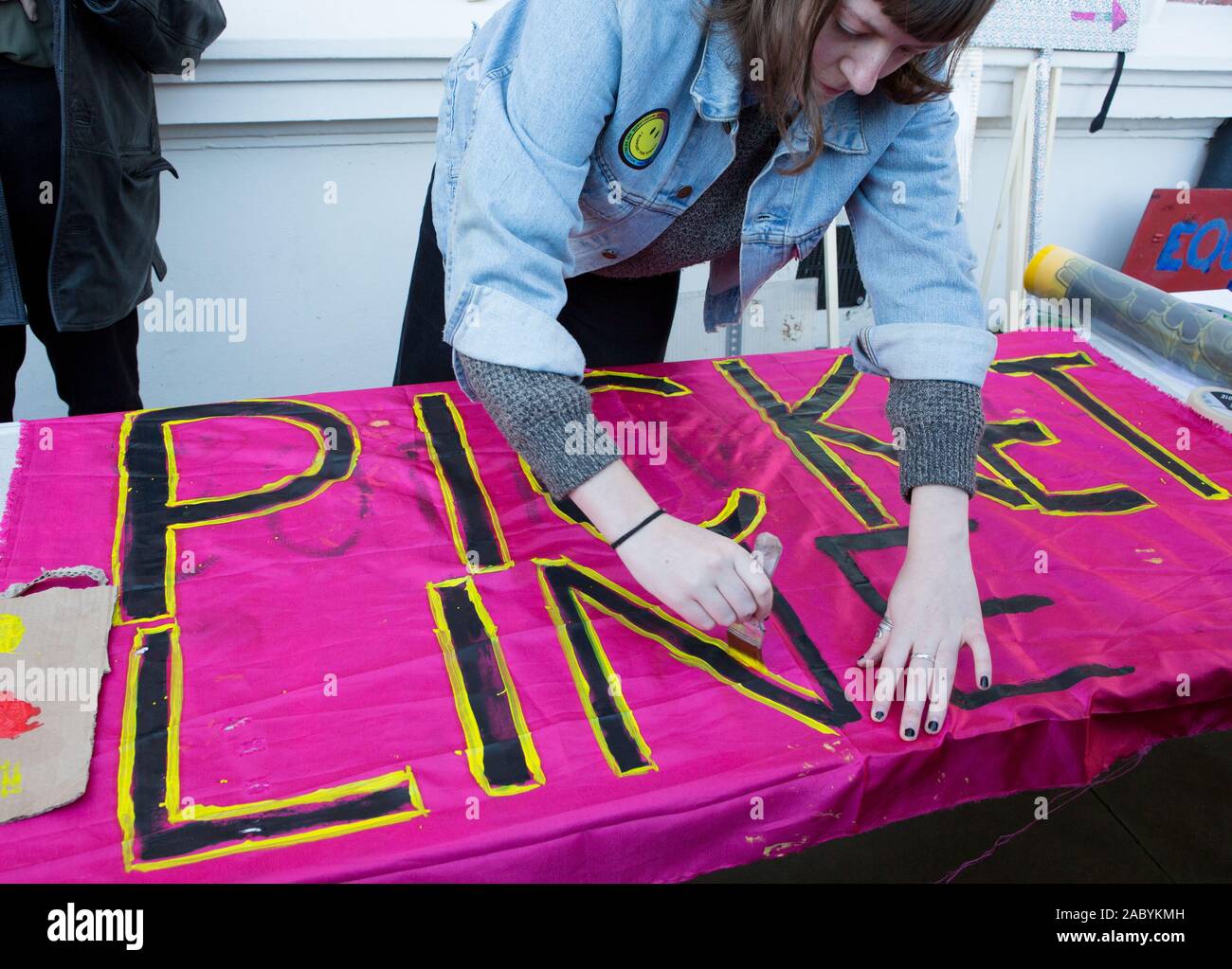 Student painting a banner saying 'picket line' during the University