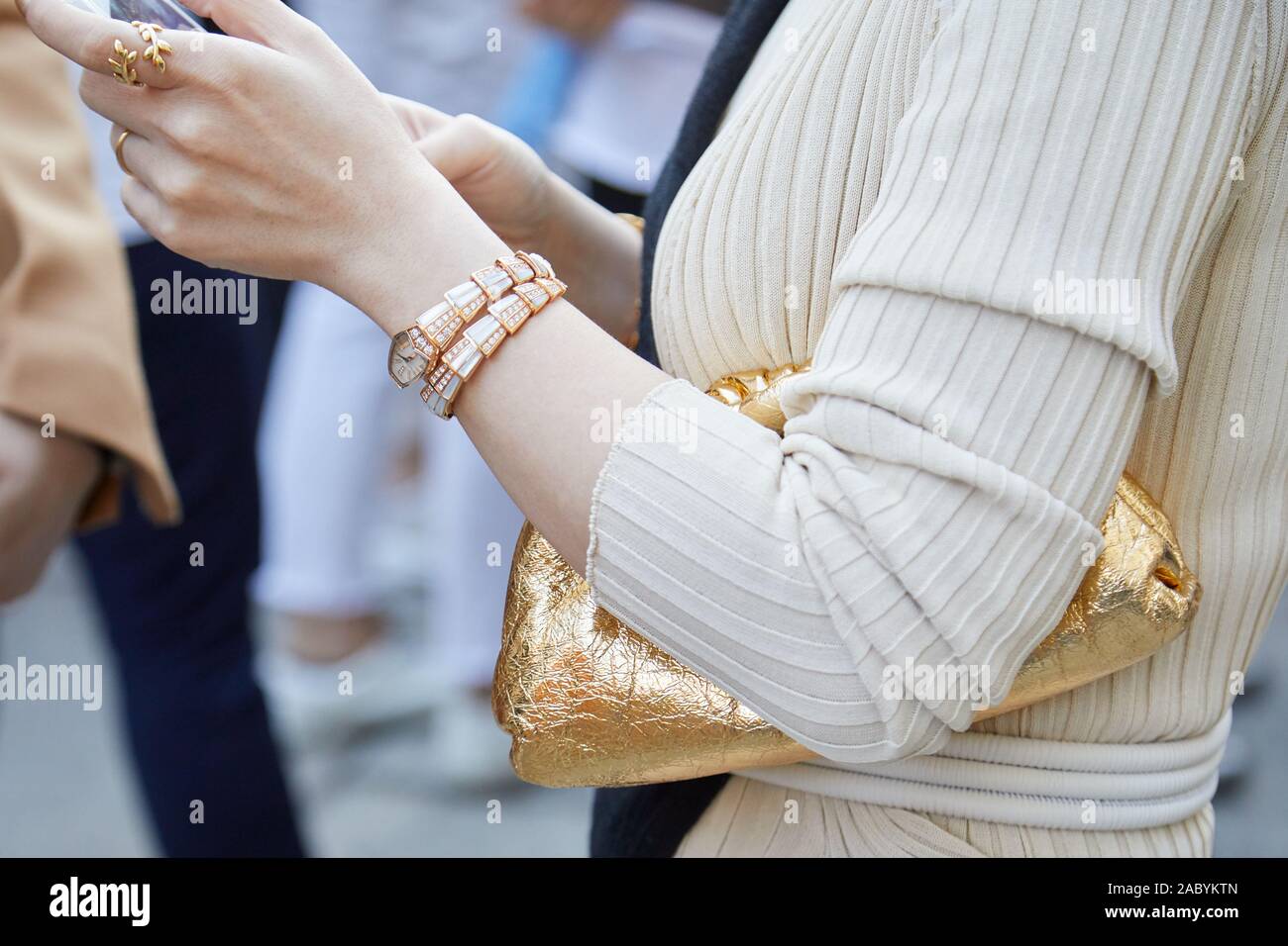 MILAN, ITALY - SEPTEMBER 19, 2019: Woman with Bulgari watch and golden metallic bag before Bottega Veneta fashion show, Milan Fashion Week street styl Stock Photo