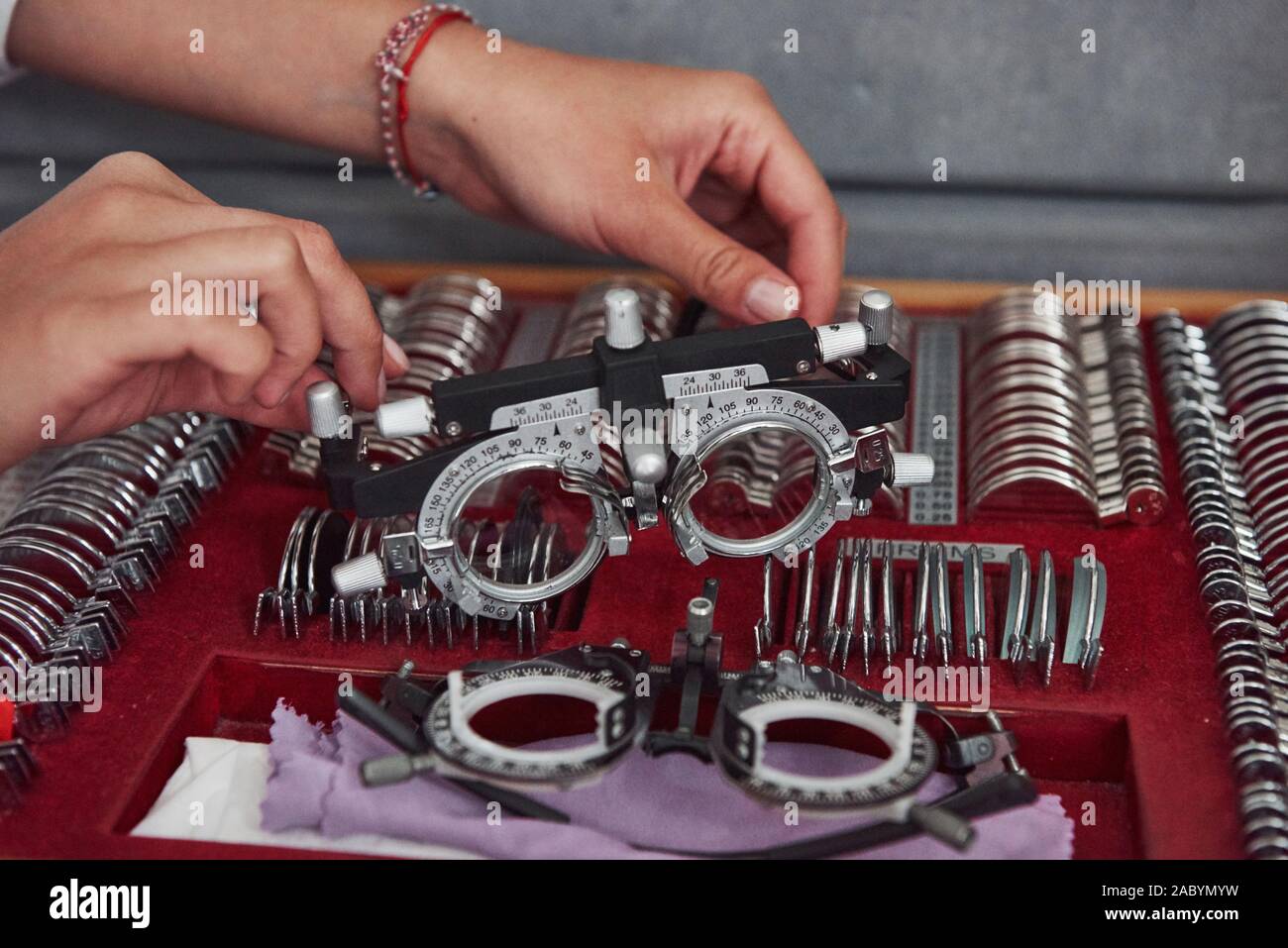 Replacement parts in below. Female hands holding the optical device for