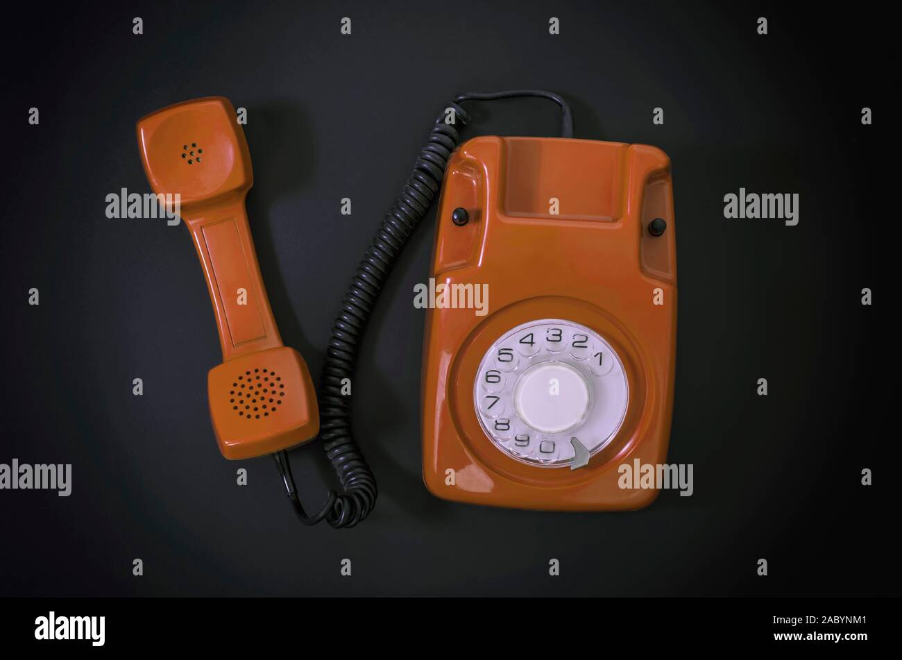 Old orange telephone rings with handset off Stock Photo