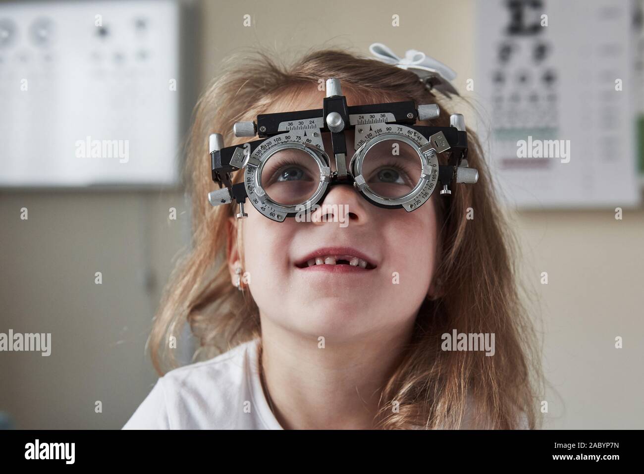 What is written there. Focused portrait of little girl in phoropter looking up Stock Photo