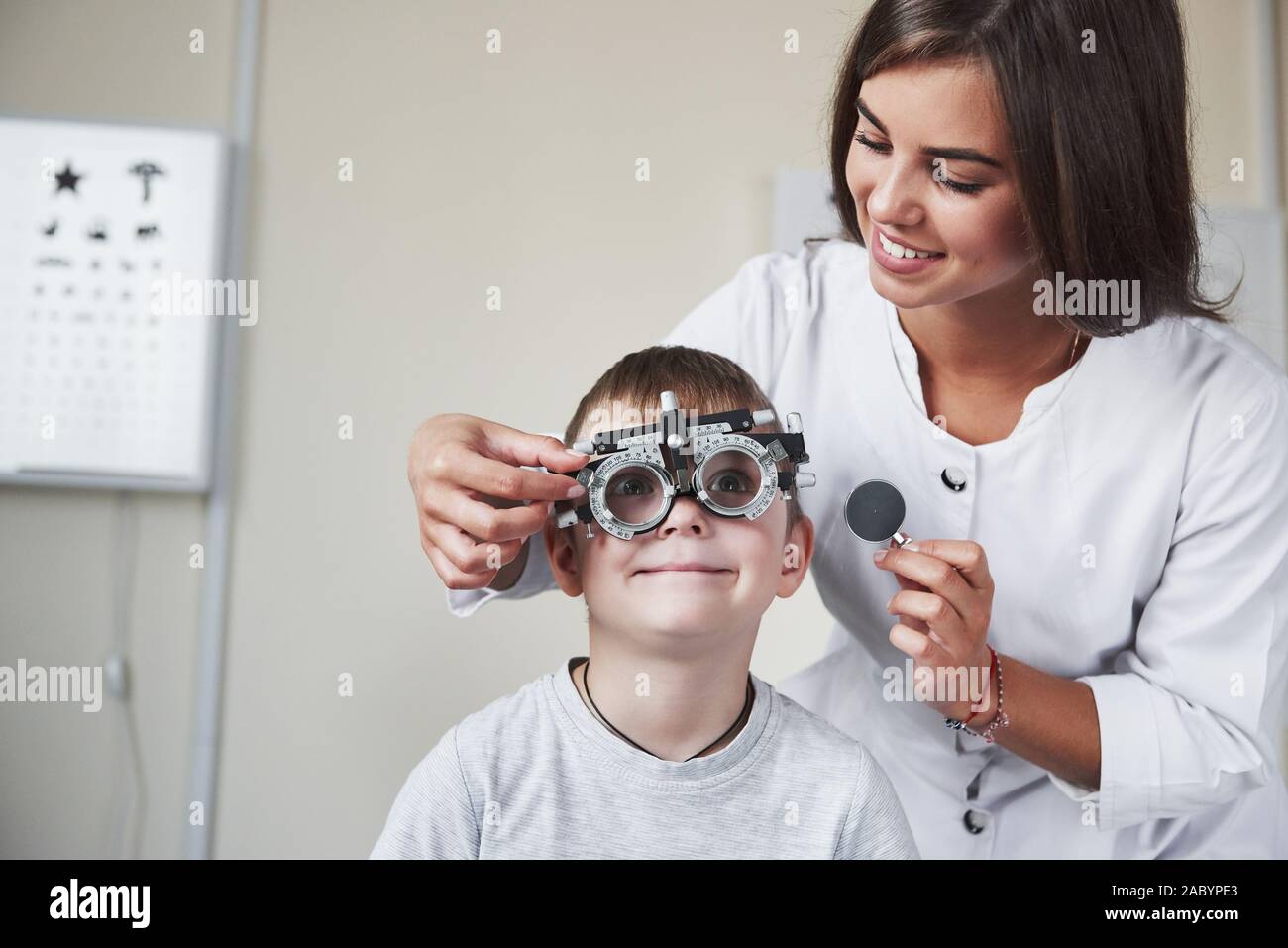 Eyes wide open. Doctor tuning the phoropter to to determine visual acuity of the little boy Stock Photo