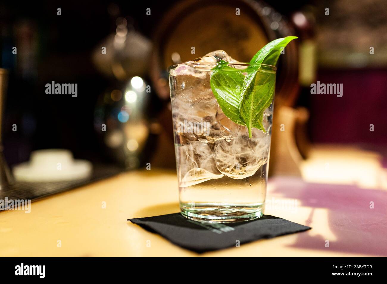 close up of gin tonic glass inside bar on top of bar counter with ice