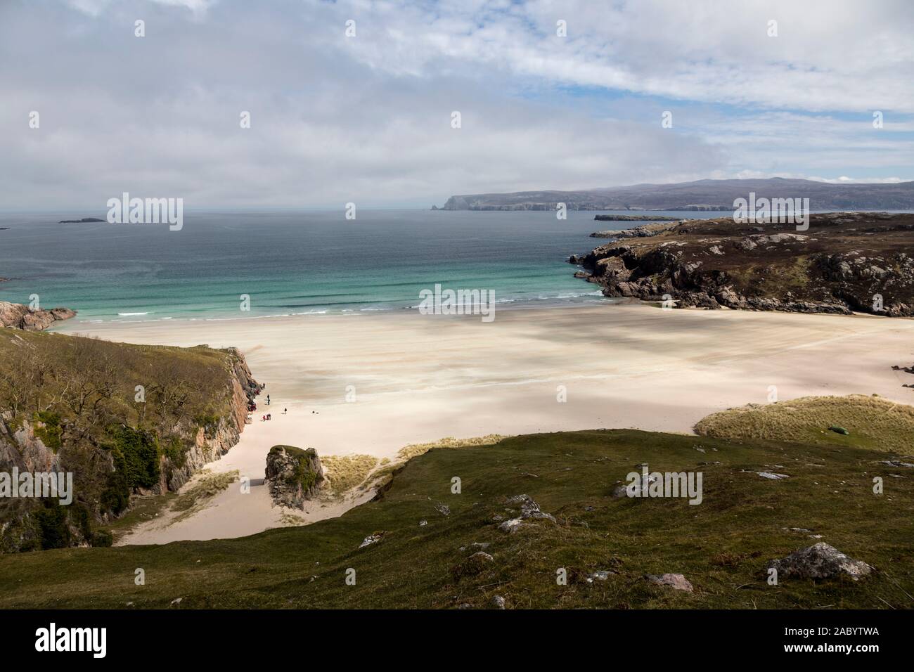 Viewed from the cliffs above, a few people enjoy the wide expanses of Ceannabeinne beach with its extensive white sands and tuquoise sea Stock Photo