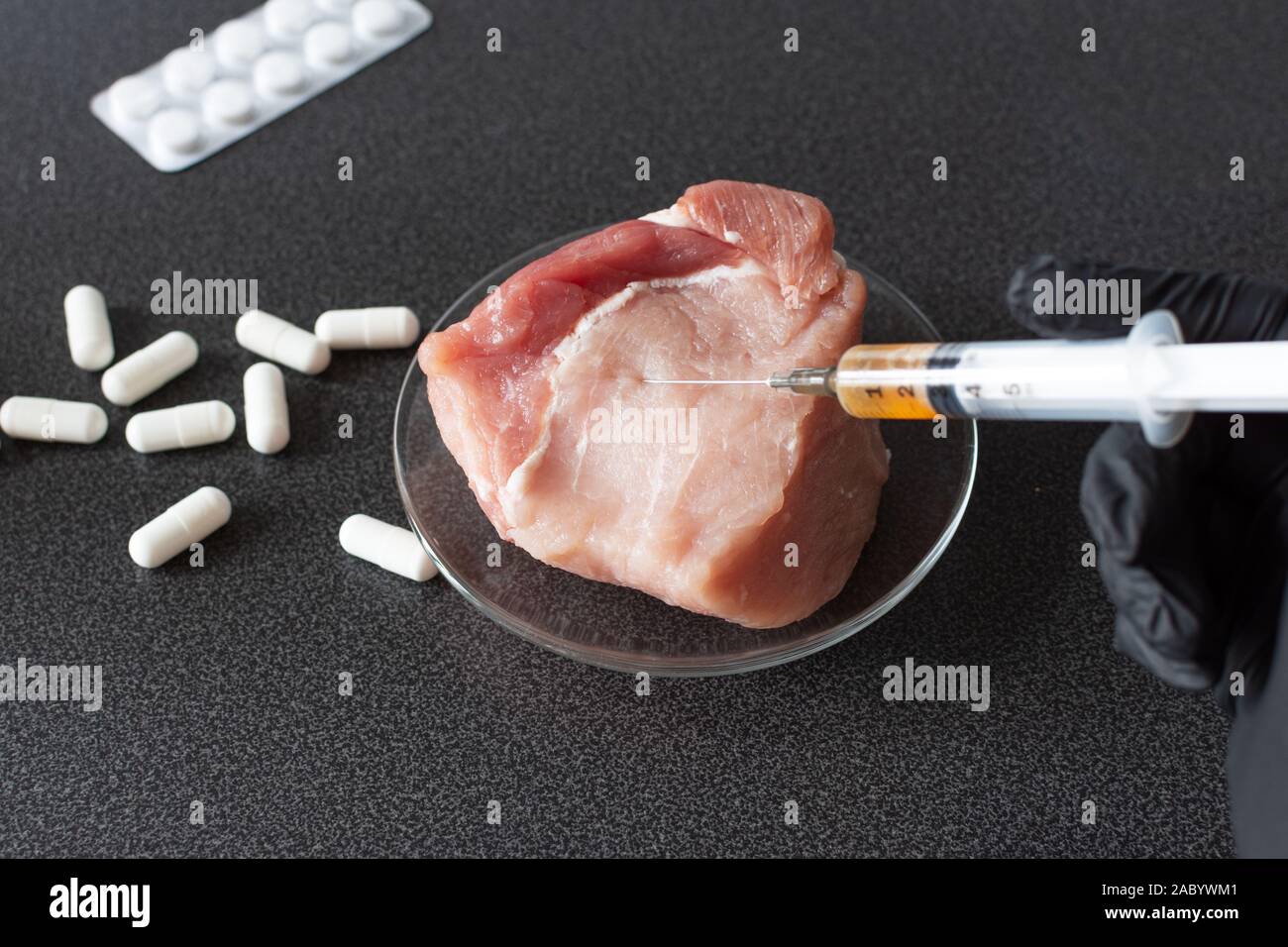 Researcher injecting GMO a slice of pork meat. Genetically modified organism, harmful for peples health. Meat with antibiotics concept. Stock Photo