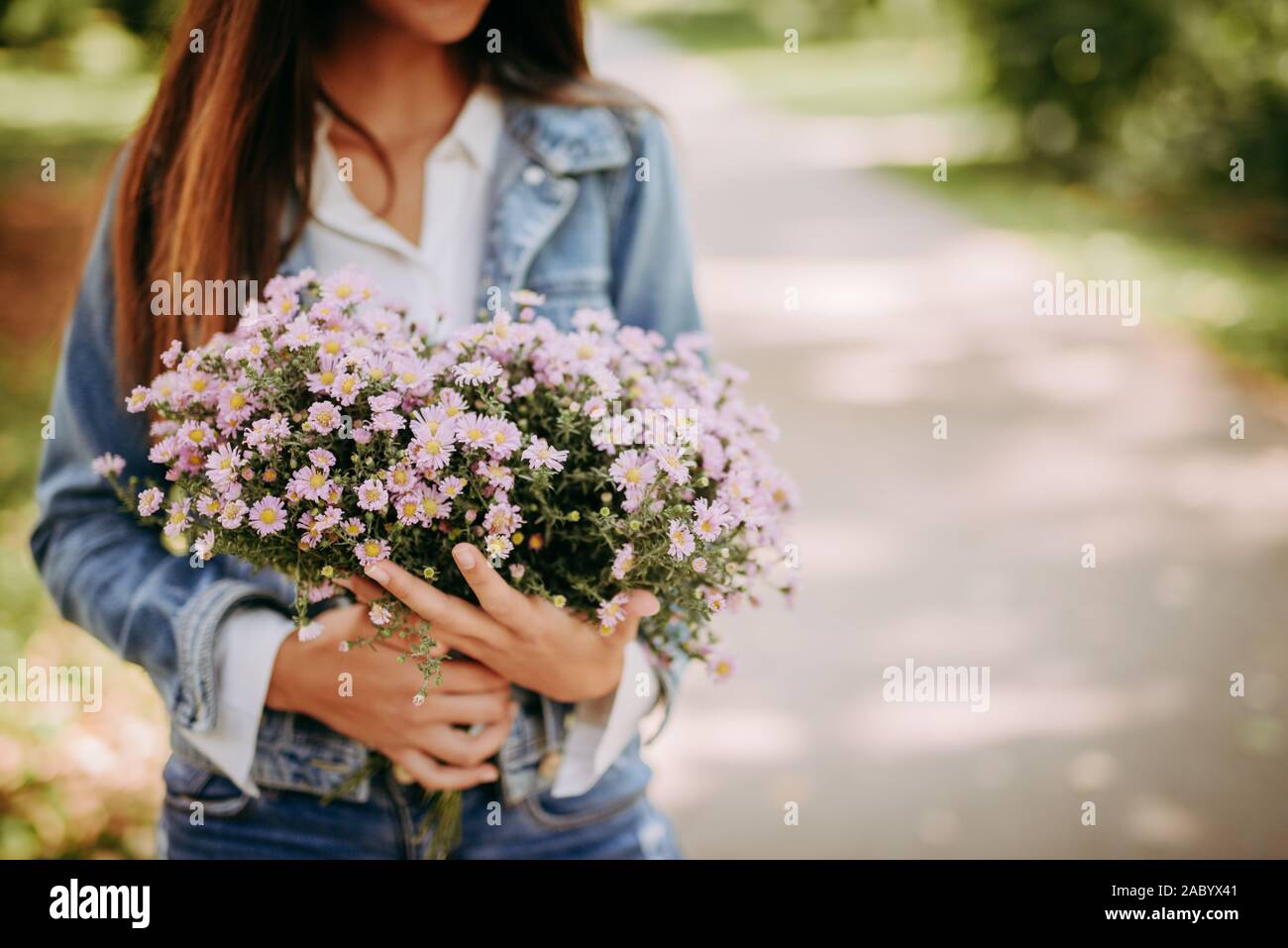Beautiful woman in park with bouquet of flowers Stock Photo - Alamy