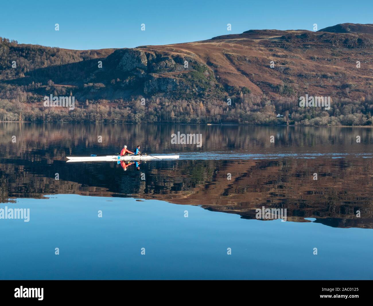 Derwentwater Keswick Cumbria, UK. 29th Nov, 2019. Peopel row across a still lake in beautiful reflections in the Lake District landscape today on a freezing and clear sunny winter day. The cold weather is set to continue over the weekend with a hard frost overnight. Credit: Julian Eales/Alamy Live News Stock Photo