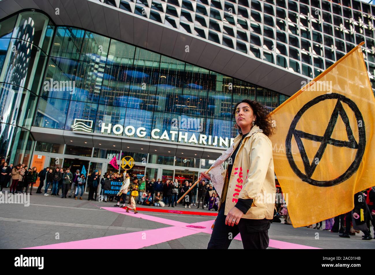 An XR female model holding a huge XR flag during the demonstration.In Utrecht, Extinction Rebellion Nederland organised an XR fashion action, against the consumerism during the Black Friday, in front of the Hoog Catharijne shopping mall which is one of the largest indoor shopping centres in The Netherlands. All the clothes that they used were second-hand and up-cycled clothes. This follows the Fridays for Future, Youth Climate Strike movements. Stock Photo