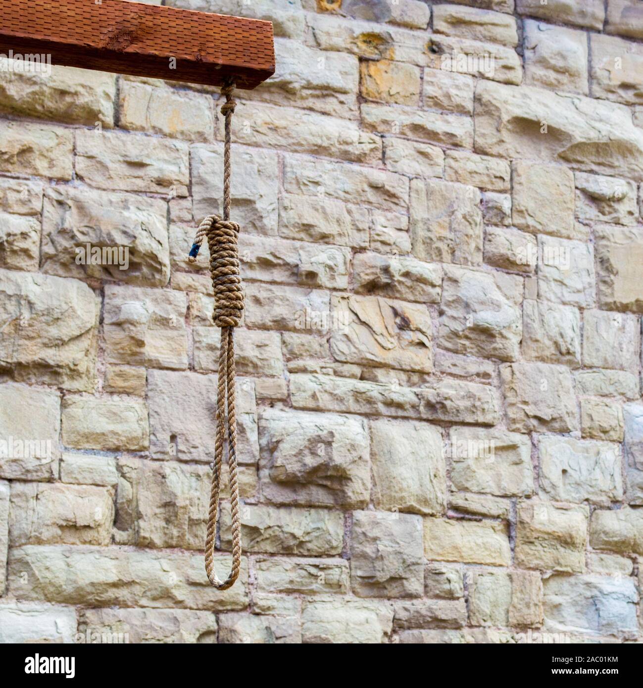 wooden prison gallows with hangman's noose against a stone wall with copy space Stock Photo