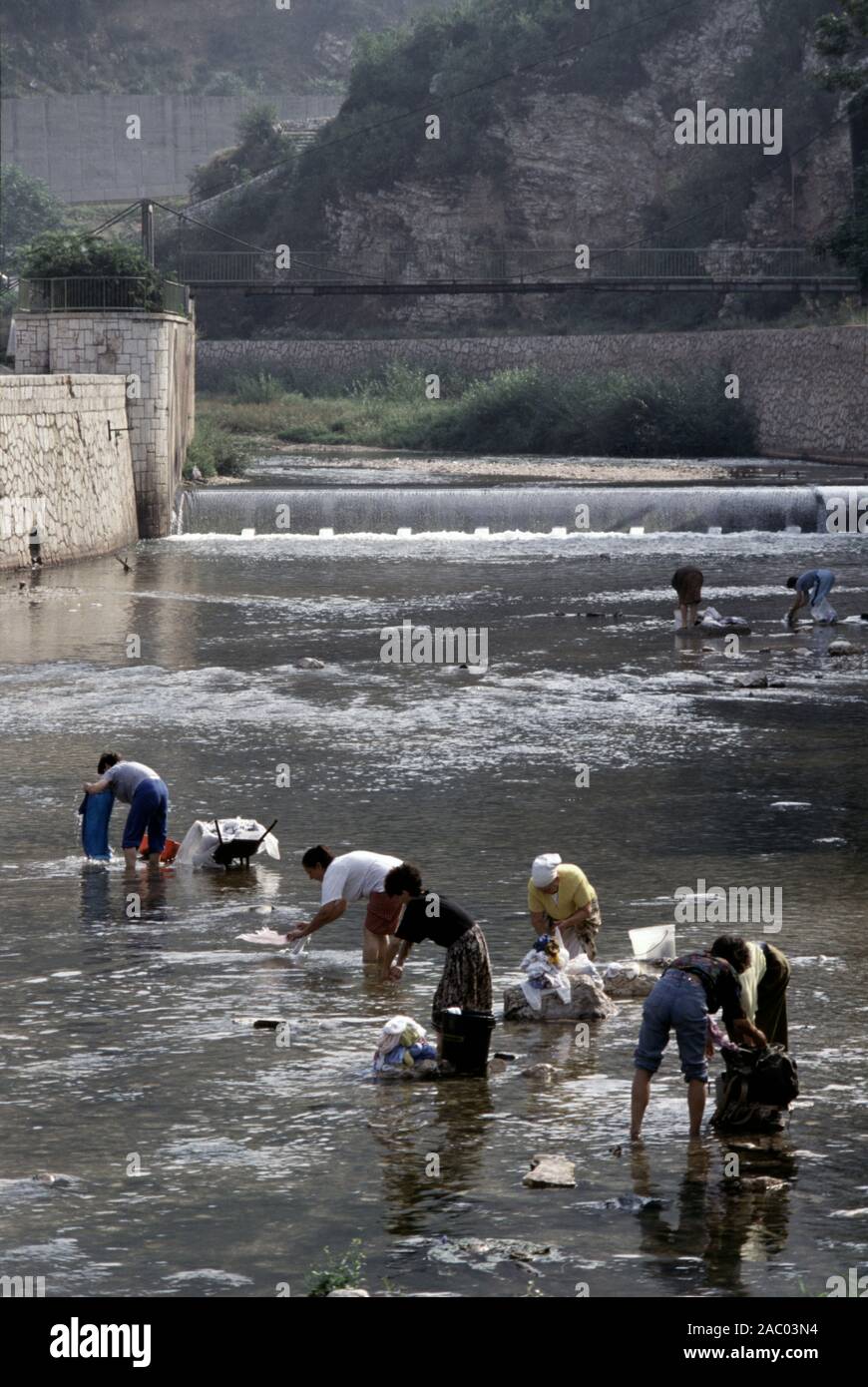 9th August 1993 During the Siege of Sarajevo: women wash laundry in the River Miljacka, just upriver from the National Art Gallery and Library. Stock Photo
