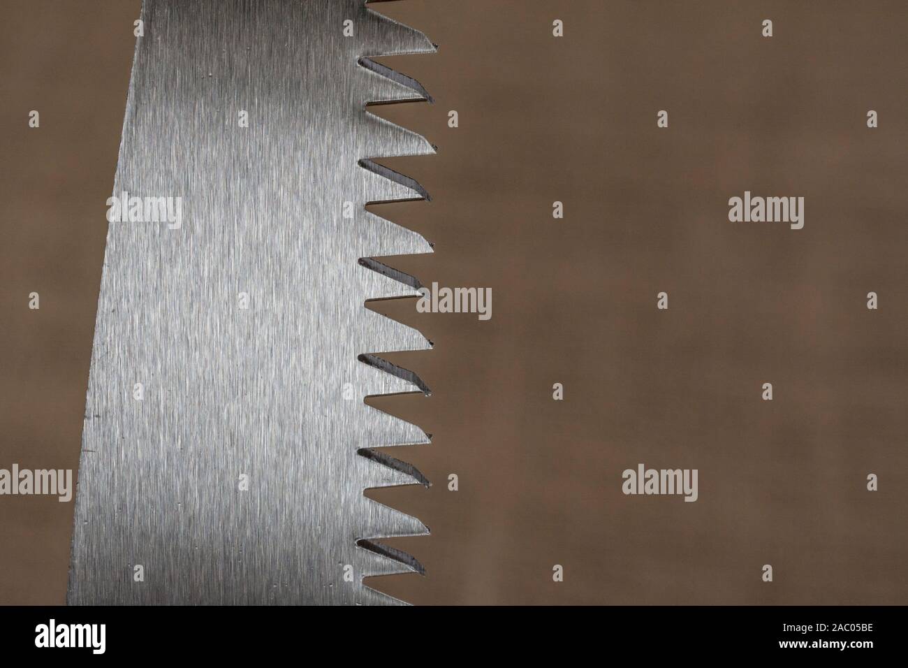 Macro close-up shot of the teeth of a short blade folding garden pruning saw. Metaphor very sharp, cutting edge, sharp teeth metal. Stock Photo