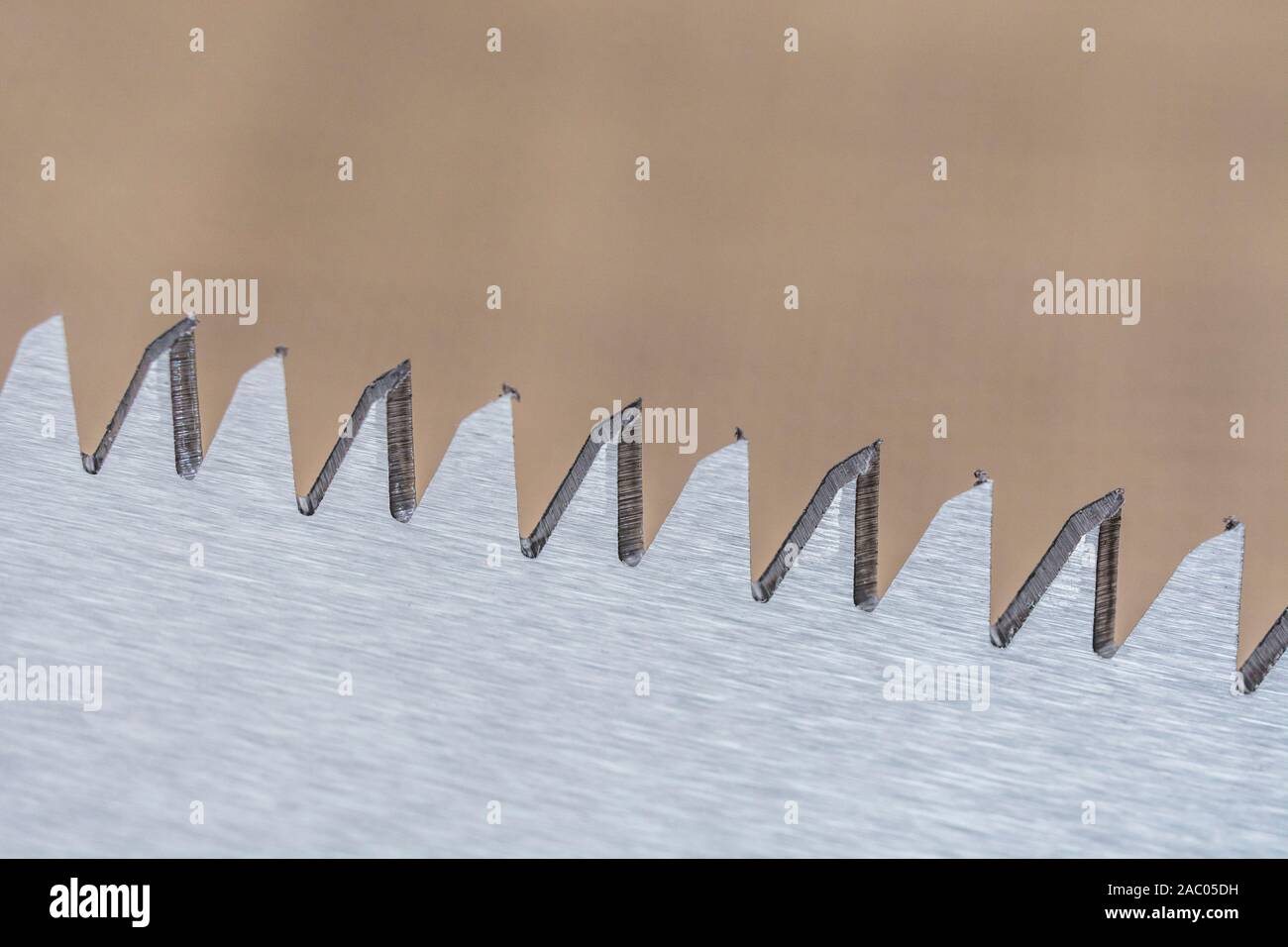 Macro close-up shot of the teeth of a short blade folding garden pruning saw. Metaphor very sharp, cutting edge, sharp teeth metal. Stock Photo