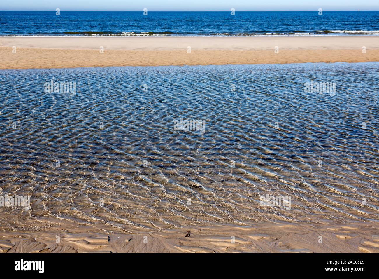 Lichtreflexe in flachem Wasser vor einer Sandbank am Weststrand auf Sylt Stock Photo