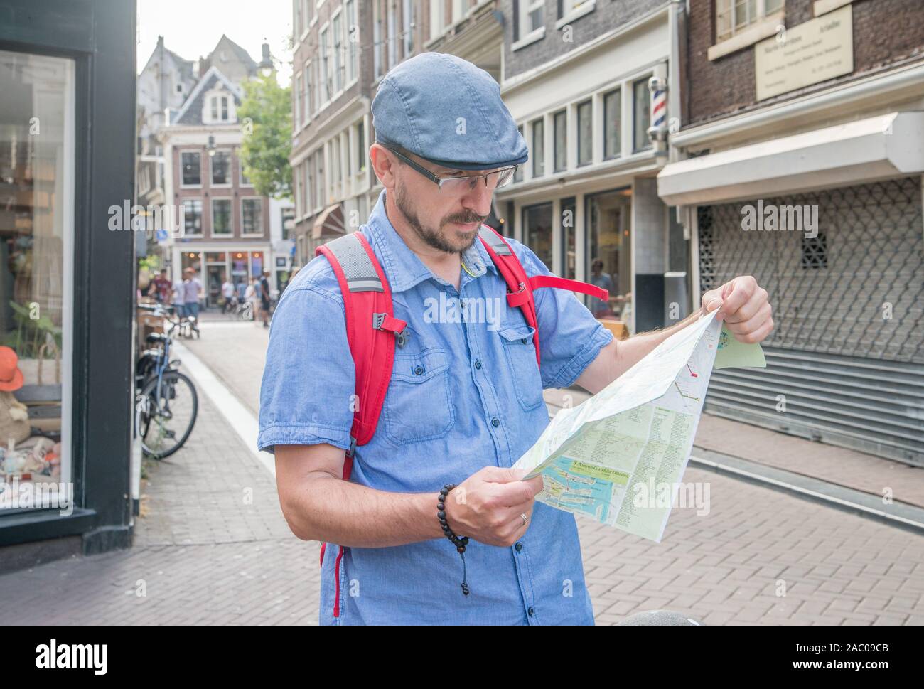 a tourist man looks at a map on a street in Amsterdam Stock Photo
