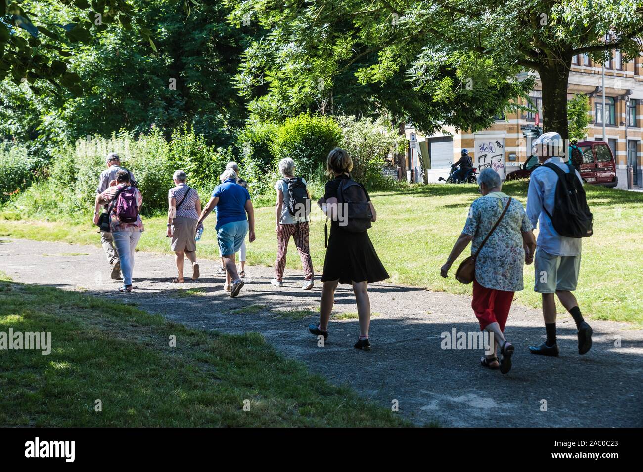 Schaerbeek, Brussels / Belgium - 06 29 2019: Group of local tourists walking in a green park Stock Photo