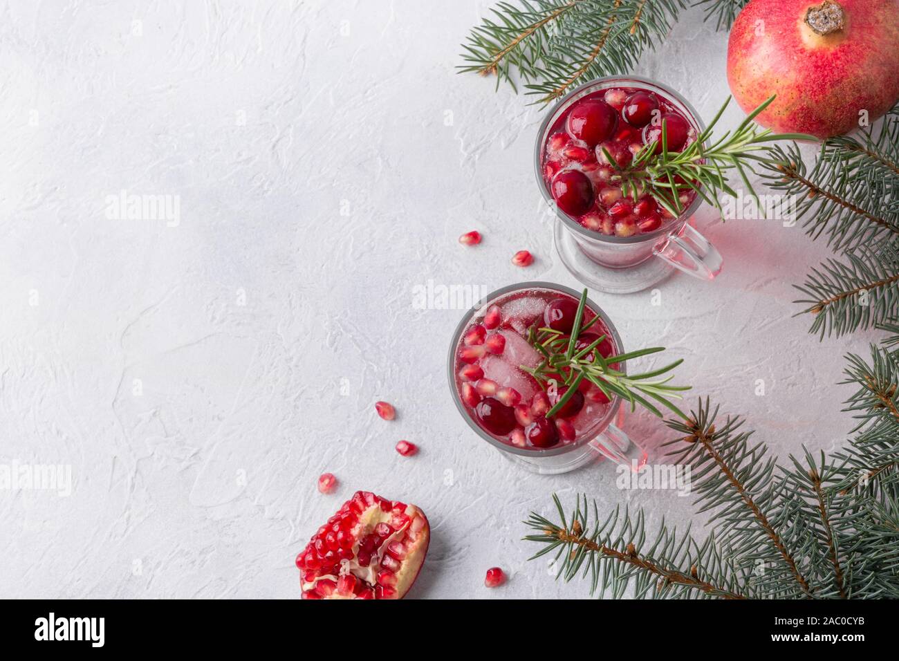 Pomegranate Christmas cocktail with rosemary, cranberry, champagne, club soda on grey concrete table. Xmas drink. View from above. Space for text. Stock Photo