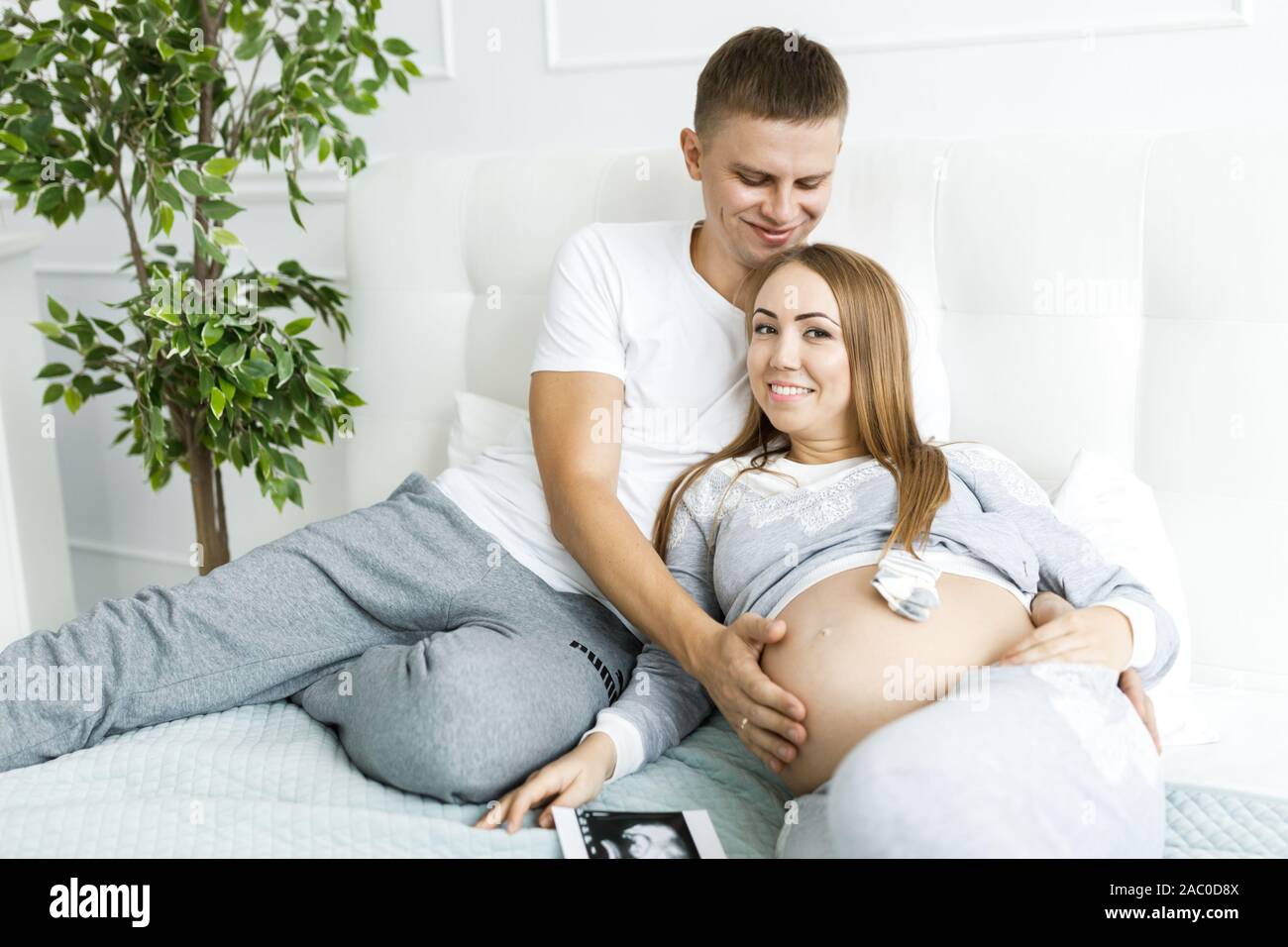 Happy Pregnant Woman and Her Husband Looking Ultrasound Scan Photo Album on  Bed Stock Image - Image of expecting, background: 141046041