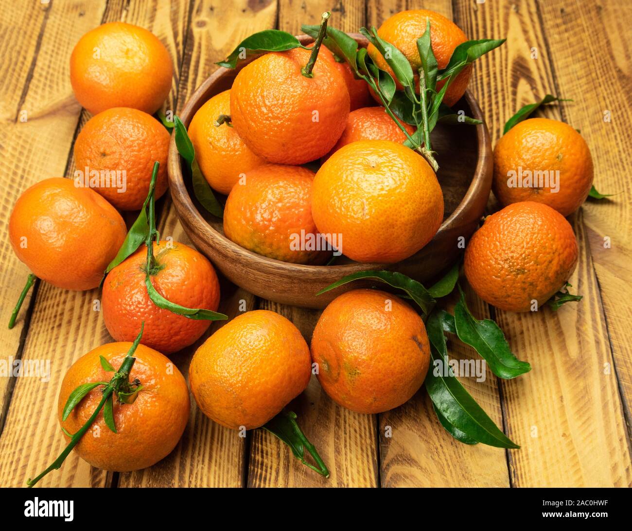 ripe organic mandarin fruits in wooden bowl over old wooden background Stock Photo