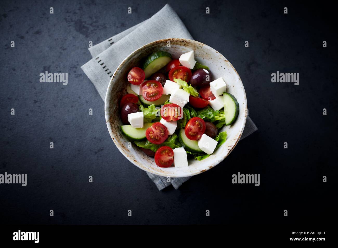 Salad with Kalamata Olives, Cucumber Cherry Tomatoes and Feta Cheese on black Stone Background Stock Photo
