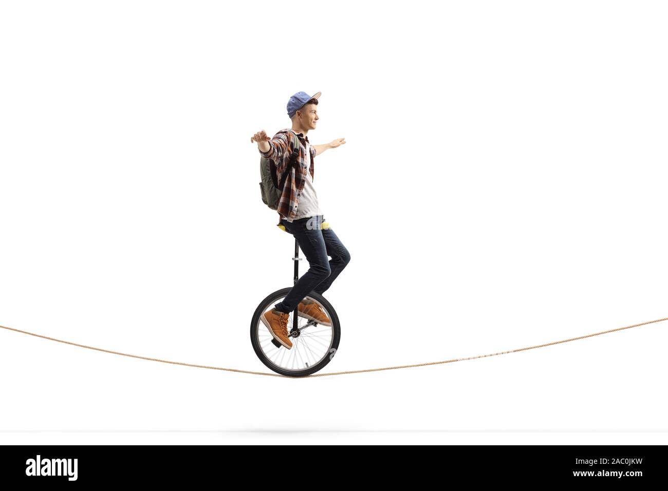 Full length shot of a male student with a backpack riding a unicycle on a rope isolated on white background Stock Photo