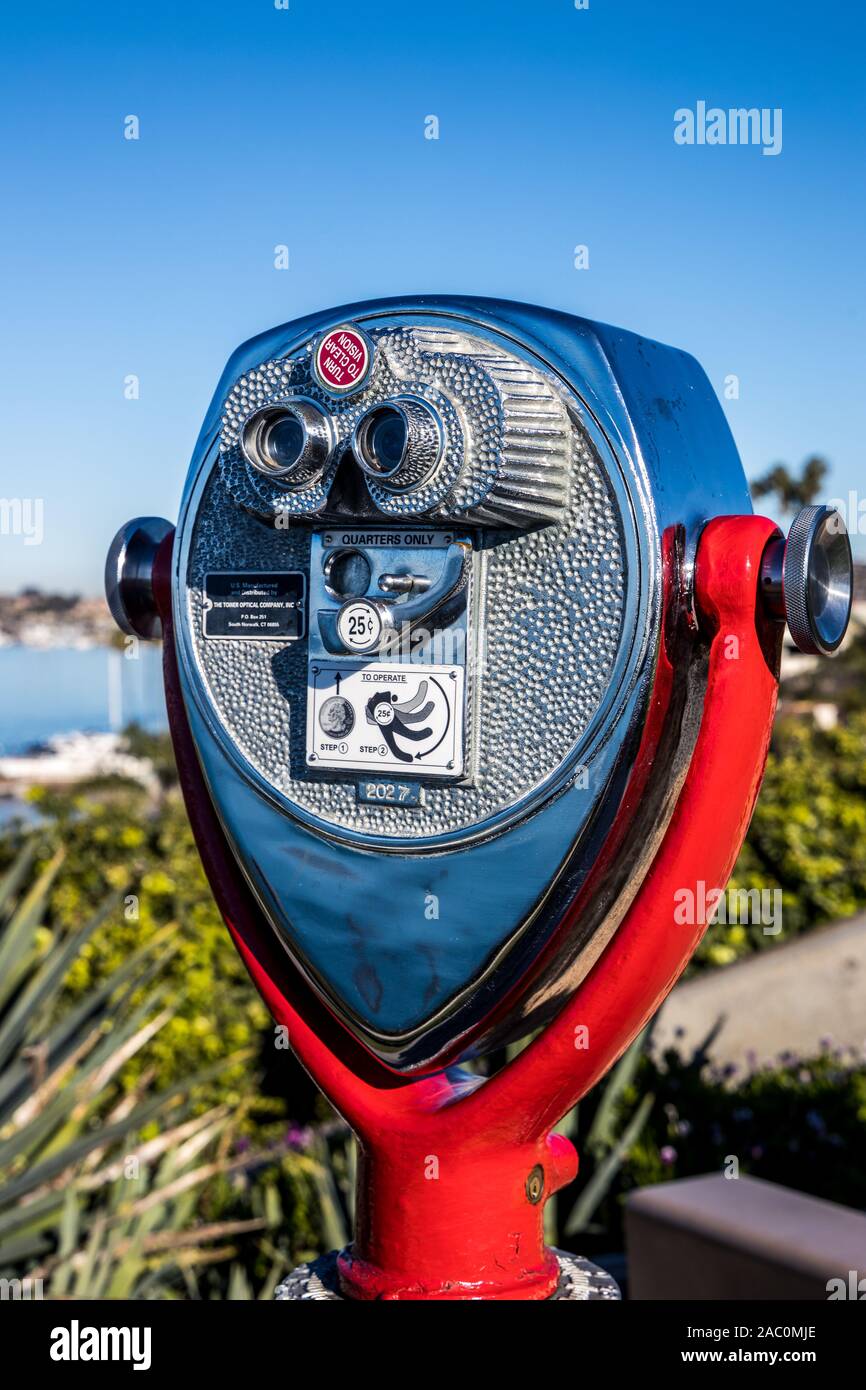 Shiny traditional coin operated binoculars coin operated binoculars for tourists, on red hinge and post with marine background, Newport Beach California Stock Photo