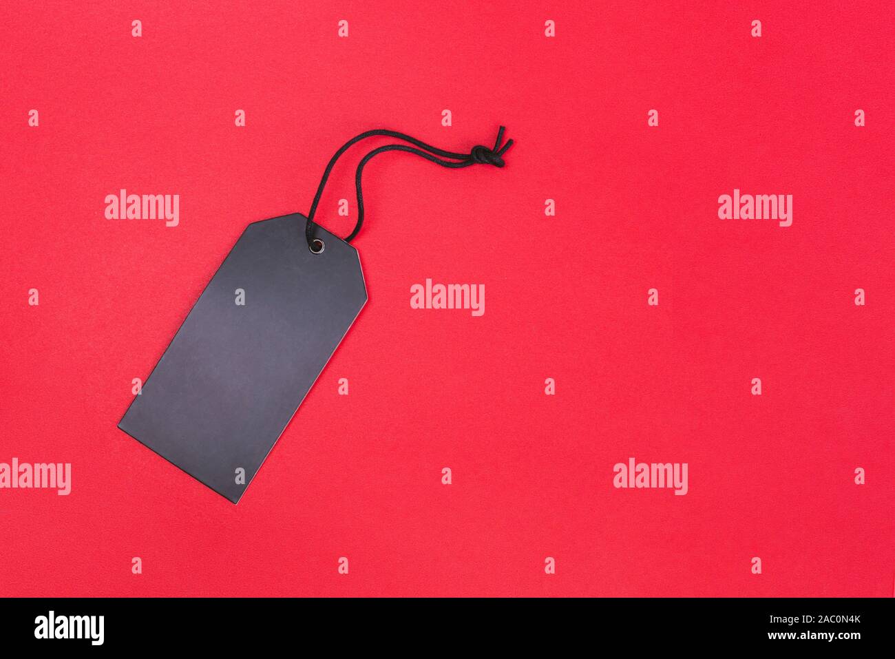 Blank black tag on red background with copy space. Price tag, gift tag, sale tag, address label