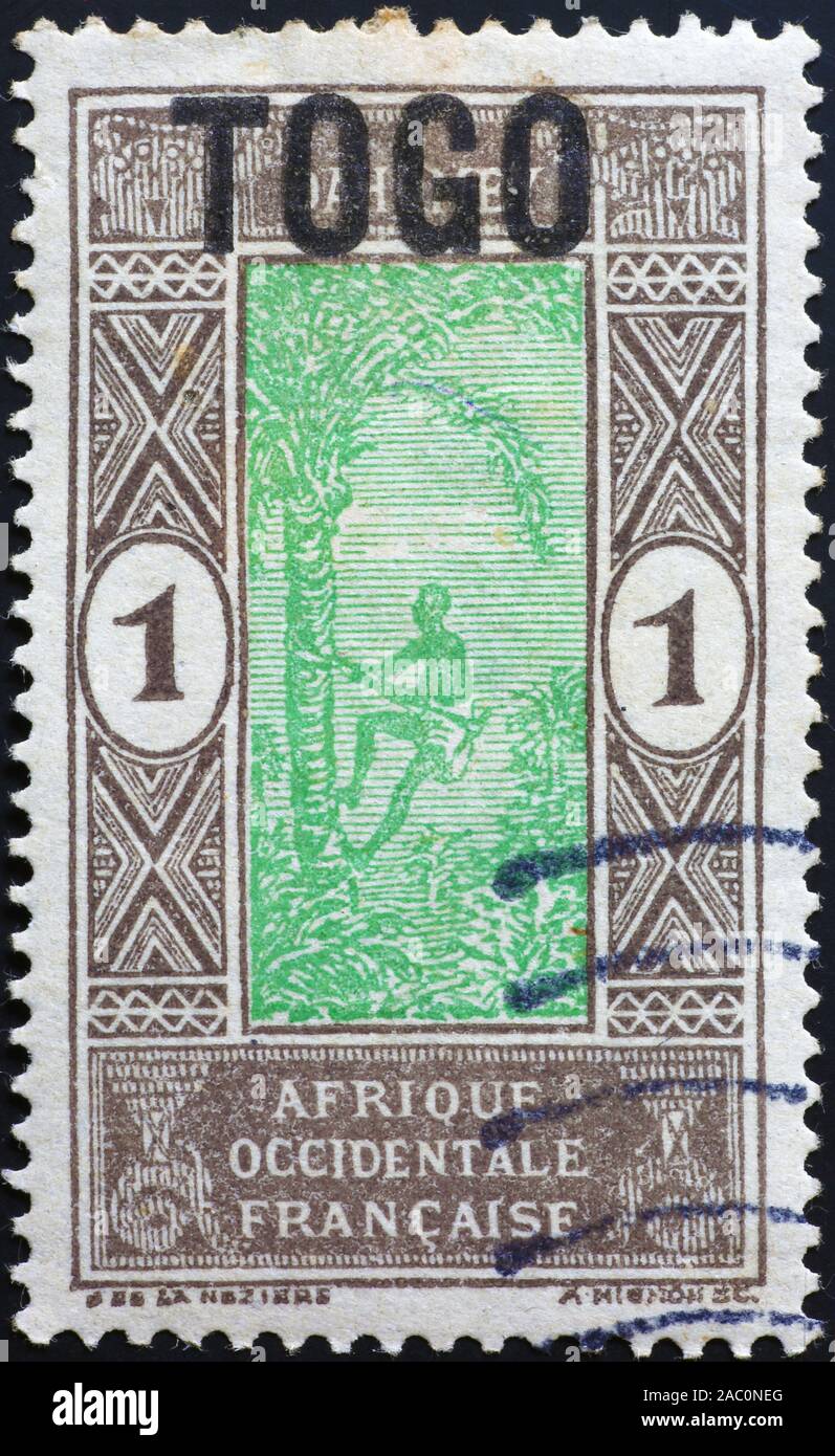 Man climbing on palm tree on old stamp of Togo Stock Photo