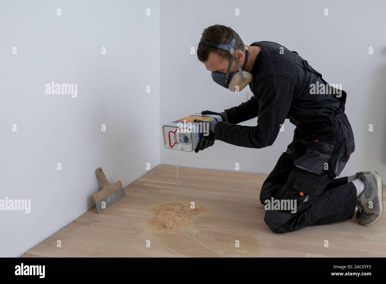 Master parquet with spatula in your hand. Preparation of parquet grout