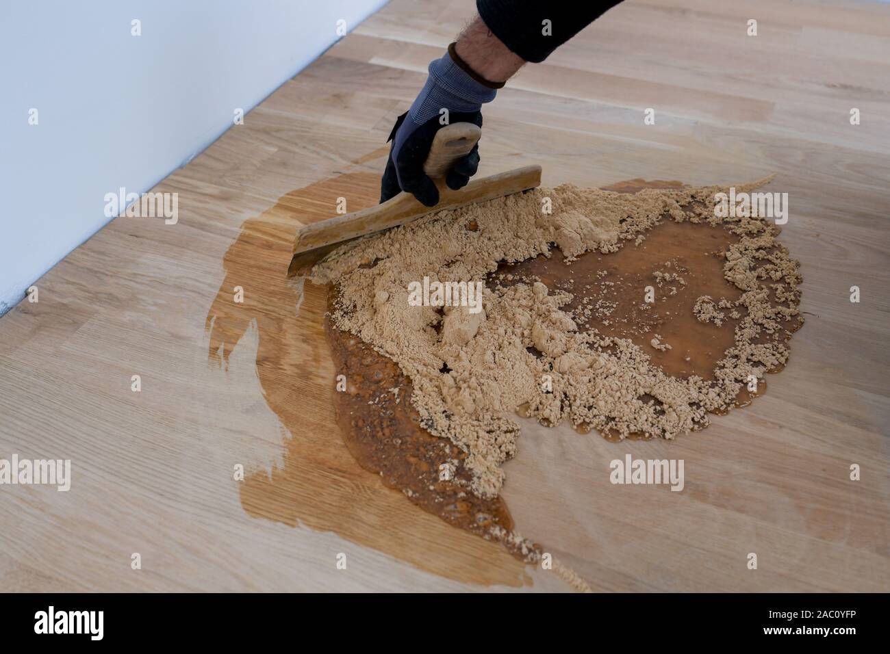 Master parquet with spatula in your hand. Preparation of parquet grout