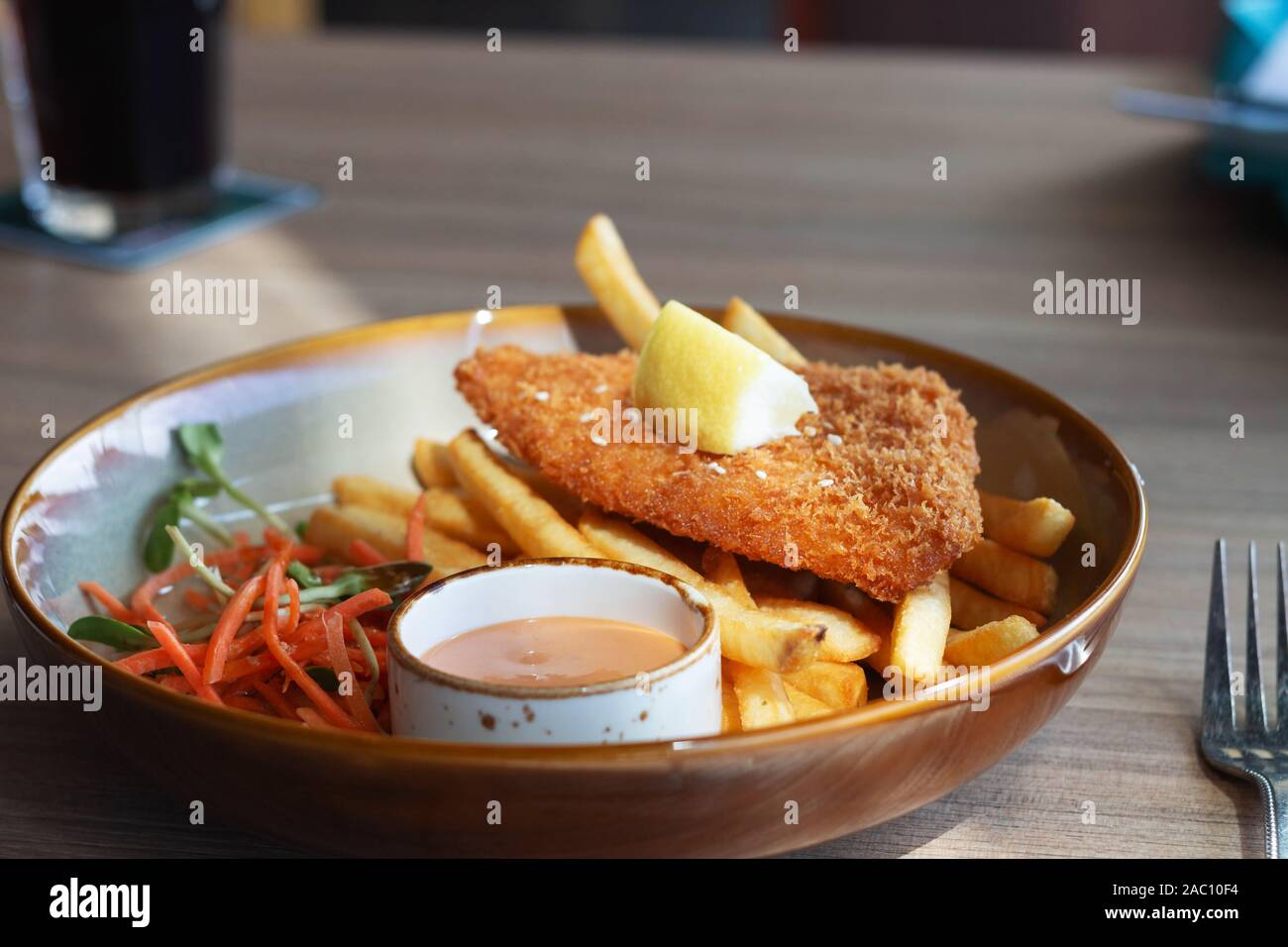 fried fish filet with french fries and veggies on plate in restaurant Stock Photo