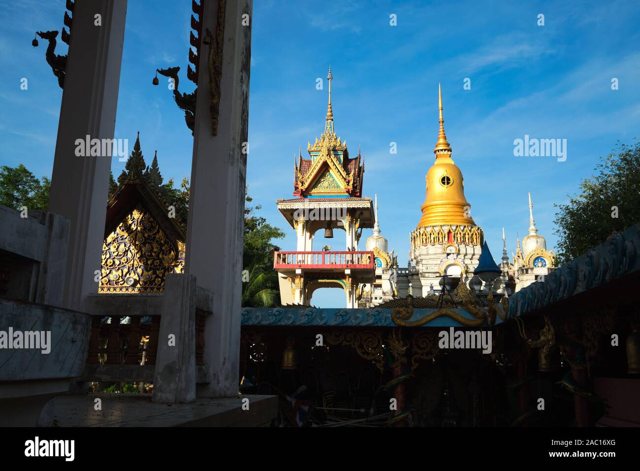 An early morning shadow-and-light view in the grounds of  Wat Phra Nang Sang, Thalang, Phuket, Thailand, with a chedi (stupa) in the background Stock Photo