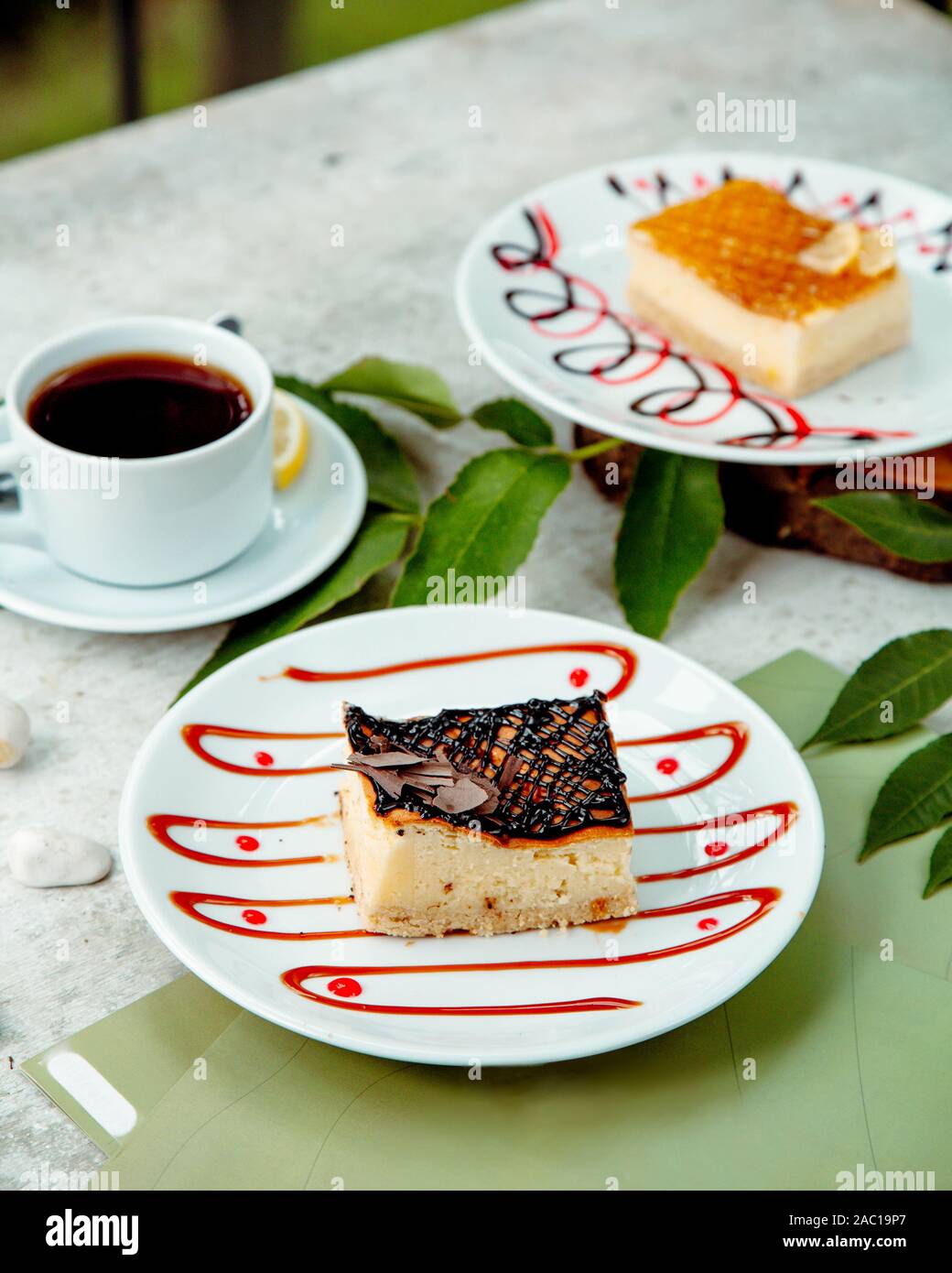 cheesecake piece garnished with chocolate syrup served with tea Stock Photo