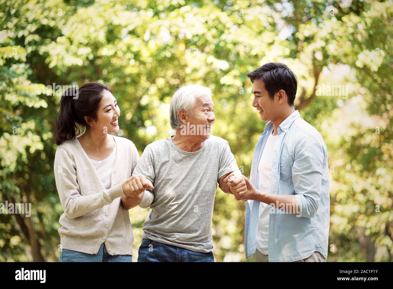 young asian man and woman helping senior man stand up and walk Stock Photo