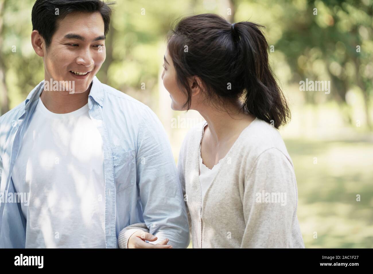 young asian couple walking talking chatting relaxing in park Stock Photo