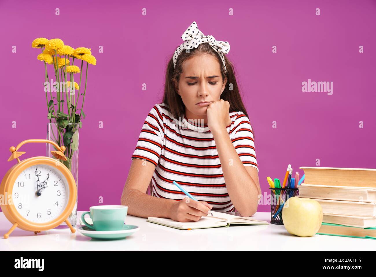 Upset Notes Attractive upset young girl sitting at the desk isolated over pink ...