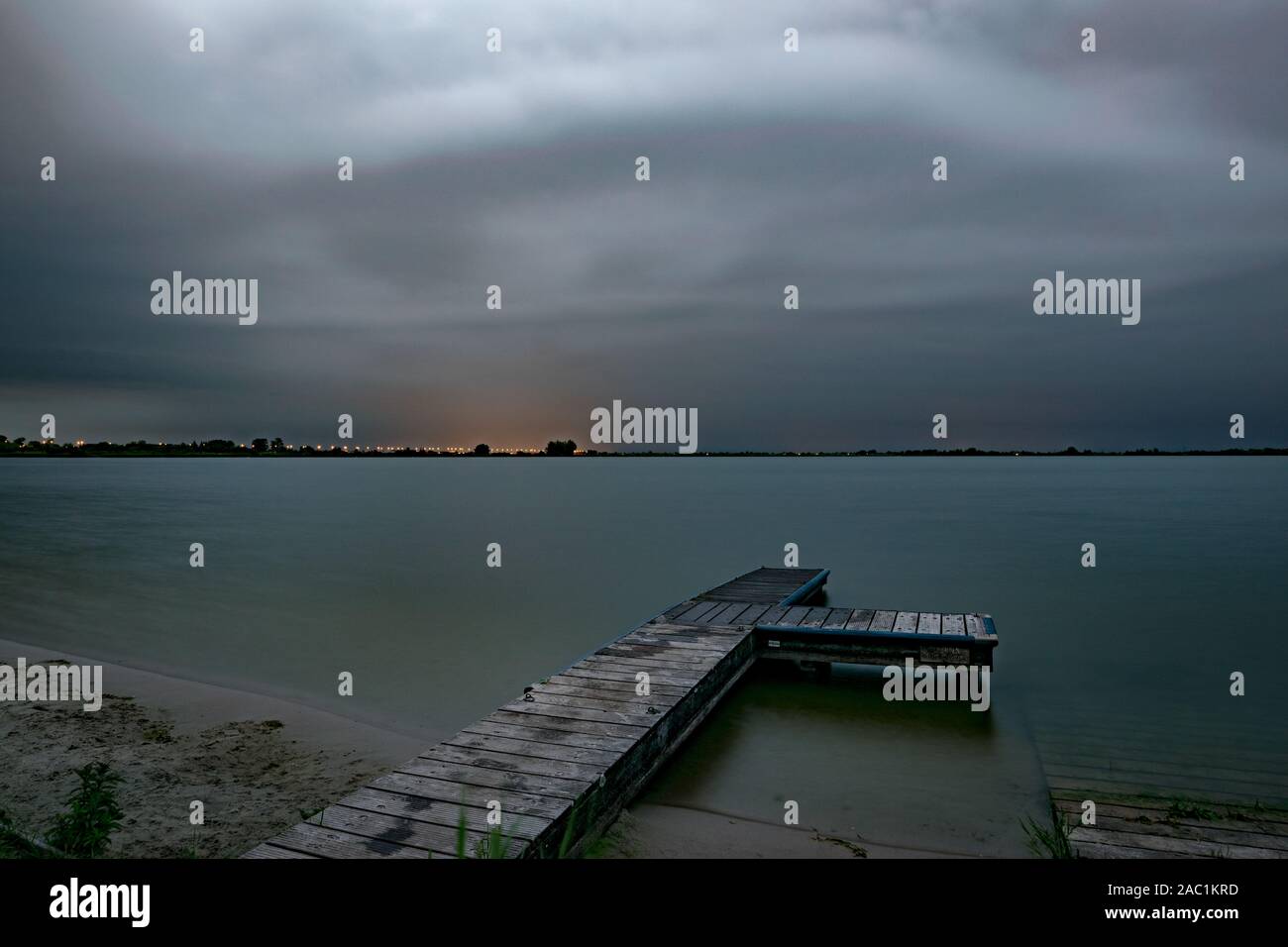Dramatic sky as a severe summer thunderstorm is approaching over a lake in The Netherlands in the evening. Stock Photo