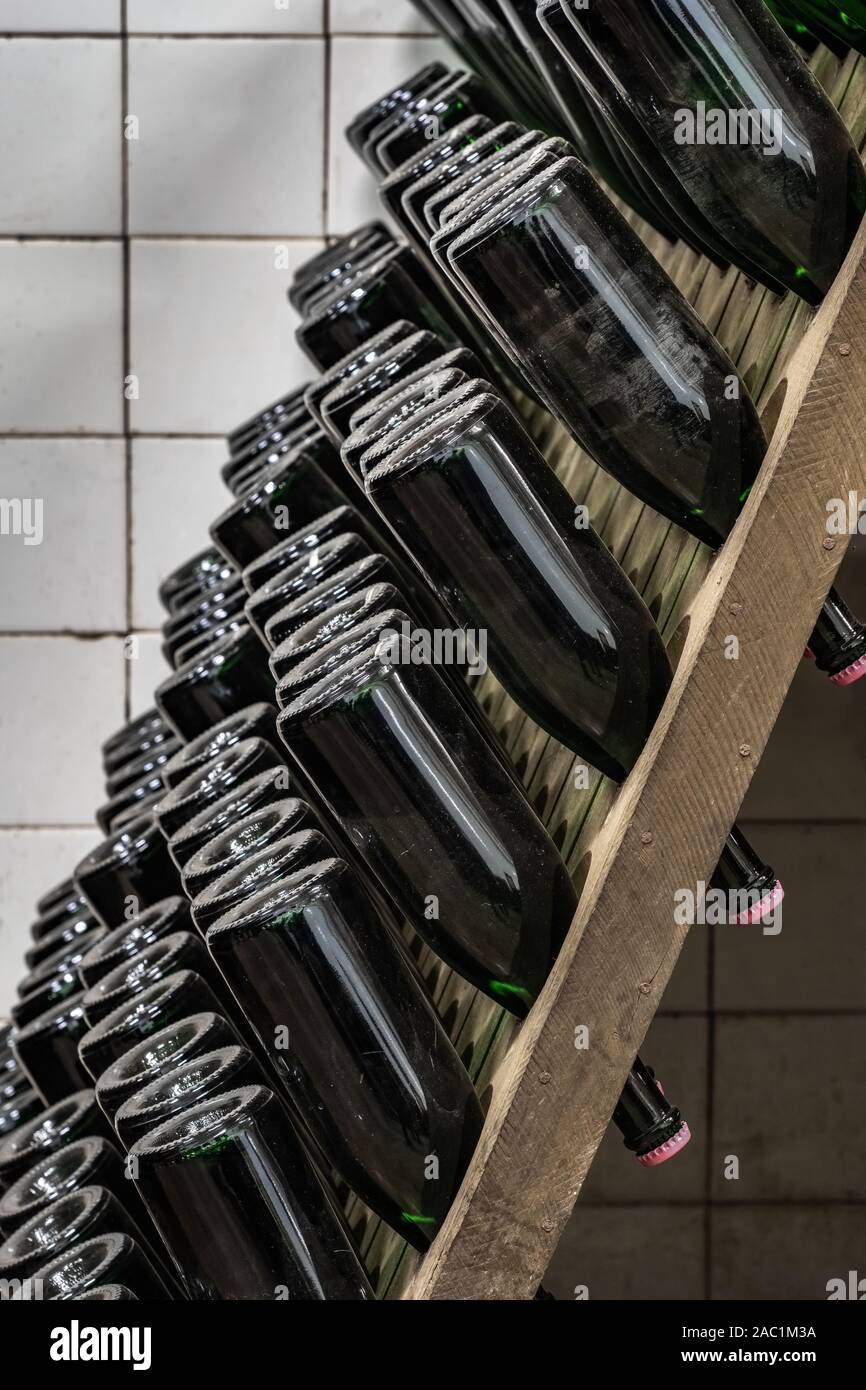 Sparkling wine bottles stacked up in old wine cellar close-up background Stock Photo